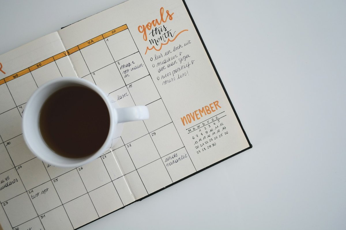 Founder planning a weekly distribution habit on a laptop calendar beside a notebook